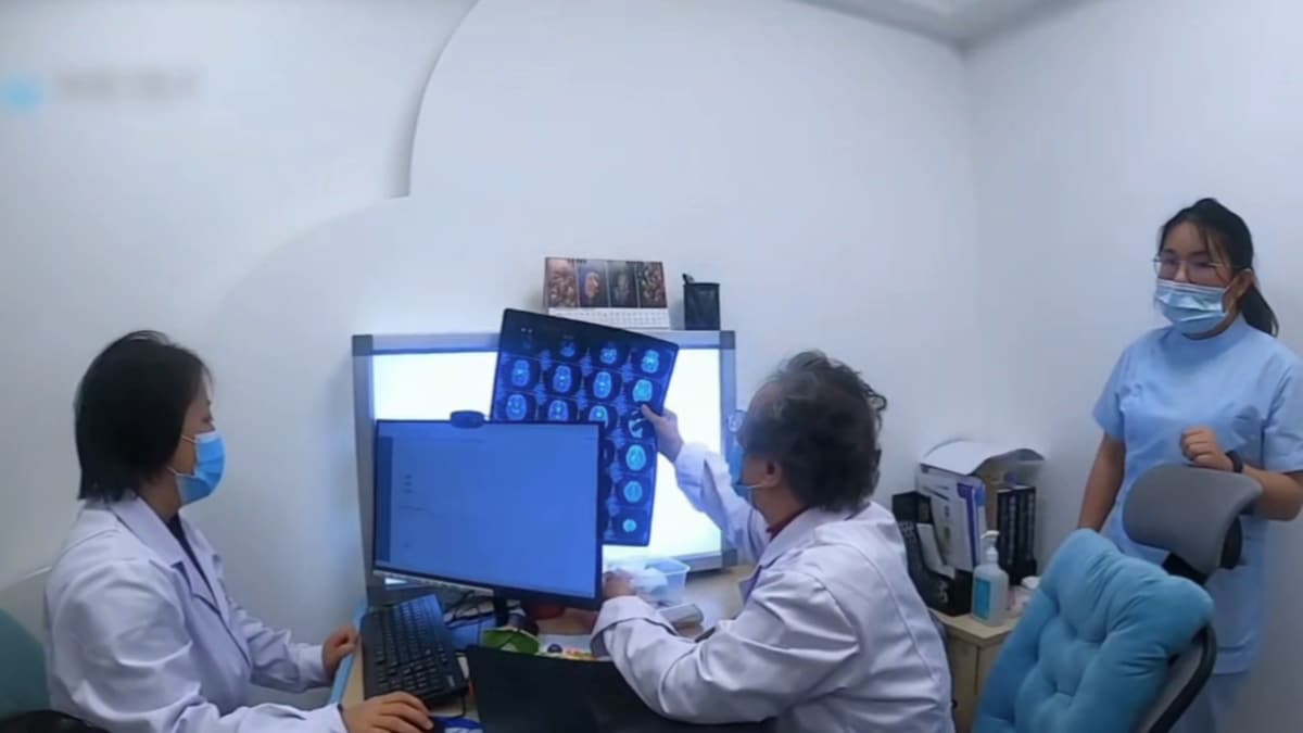诊室内,两位医生在阅片屏前会诊,一位护士在旁
