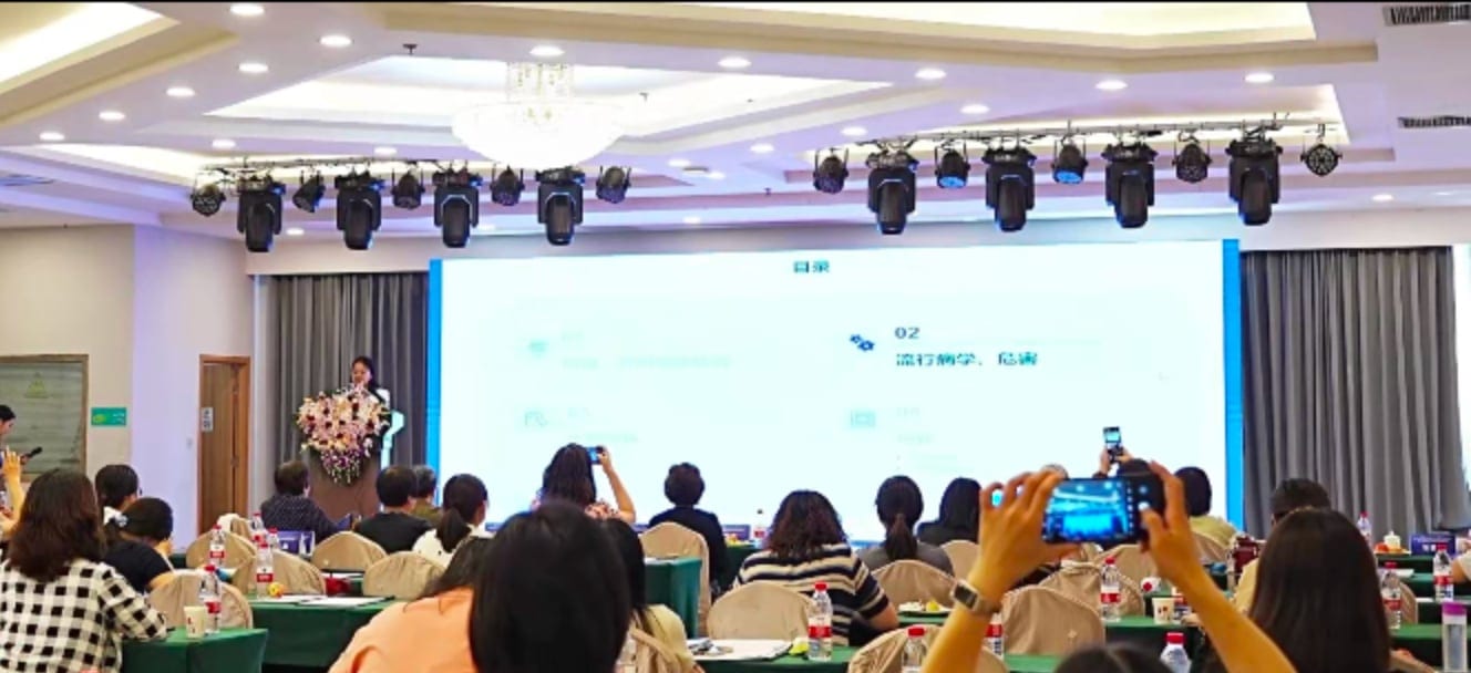 韩颖教授在会场前方讲台作报告,前排听众举着手机拍摄幻灯片