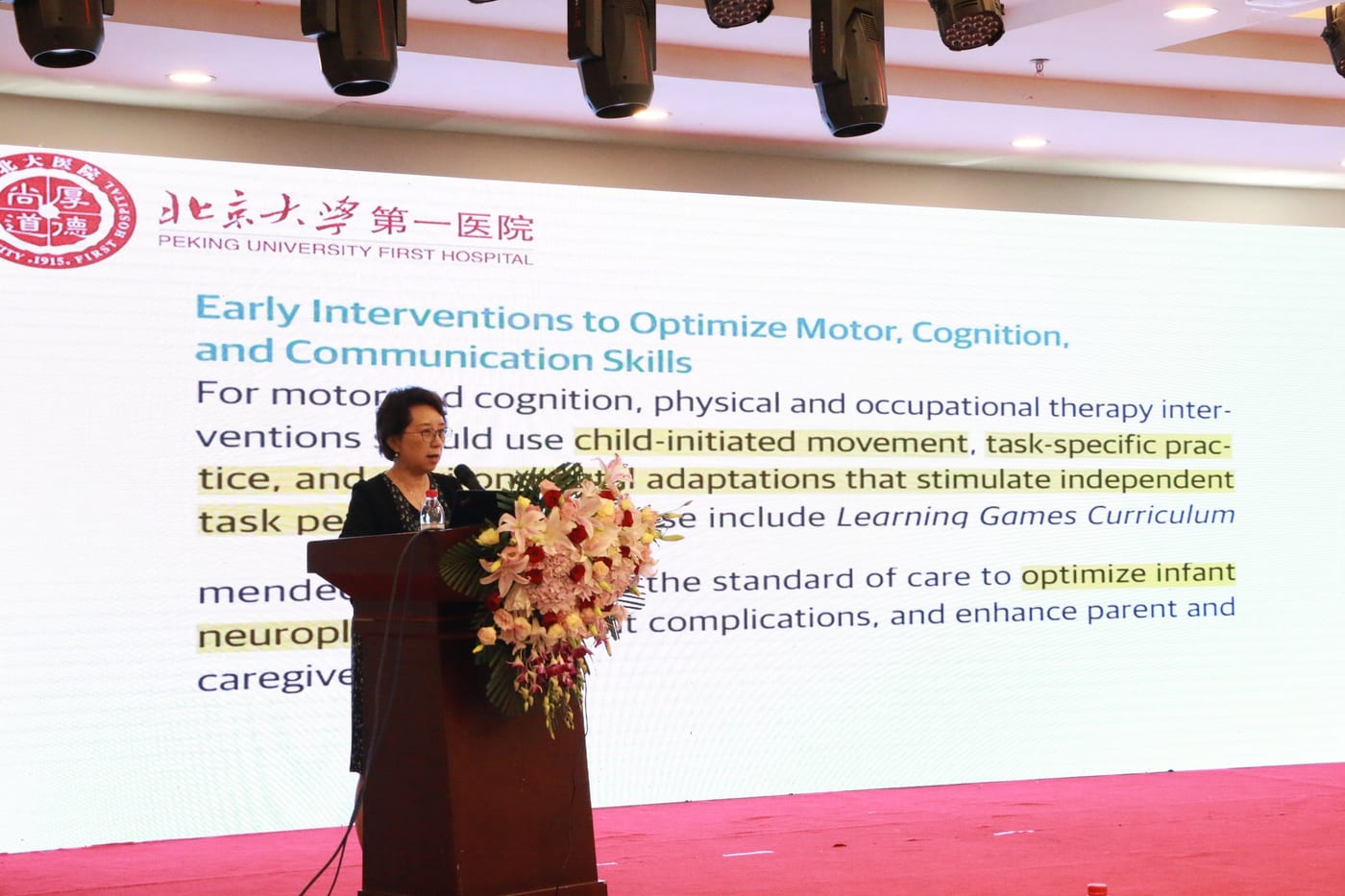 黄真教授在讲台前作报告,大屏幻灯片是英文的早期干预内容,页眉为北京大学第一医院