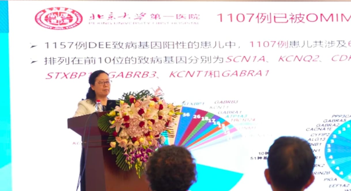 张月华教授在讲台后作报告,幻灯片上列着发育性癫痫性脑病的致病基因