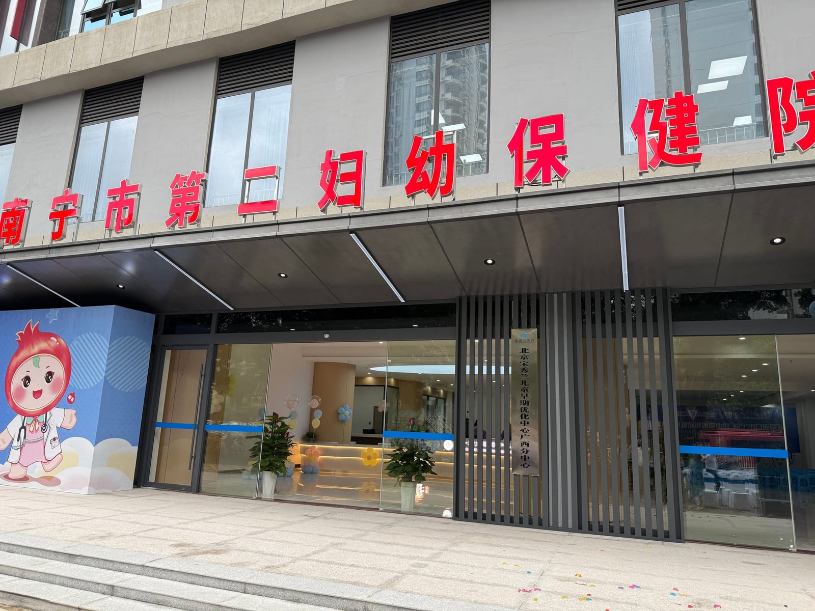 南宁市第二妇幼保健院的楼门口,门边竖挂着「北京宝秀兰儿童早期优化中心广西分中心」的牌子