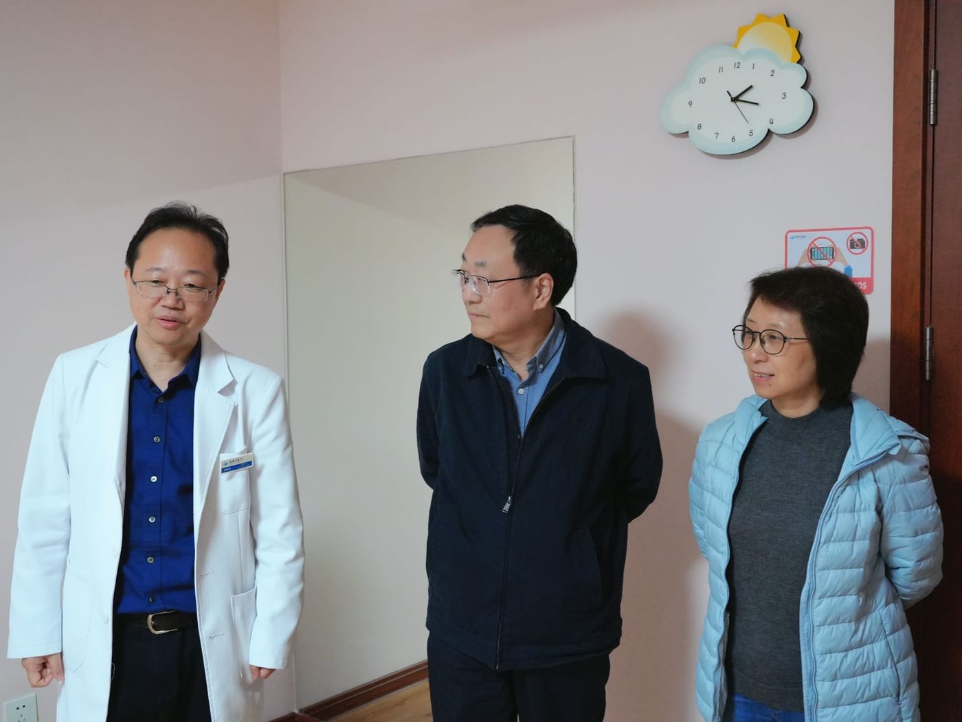 刘维民身穿白大褂,陪同两位来访者在训练室里交谈